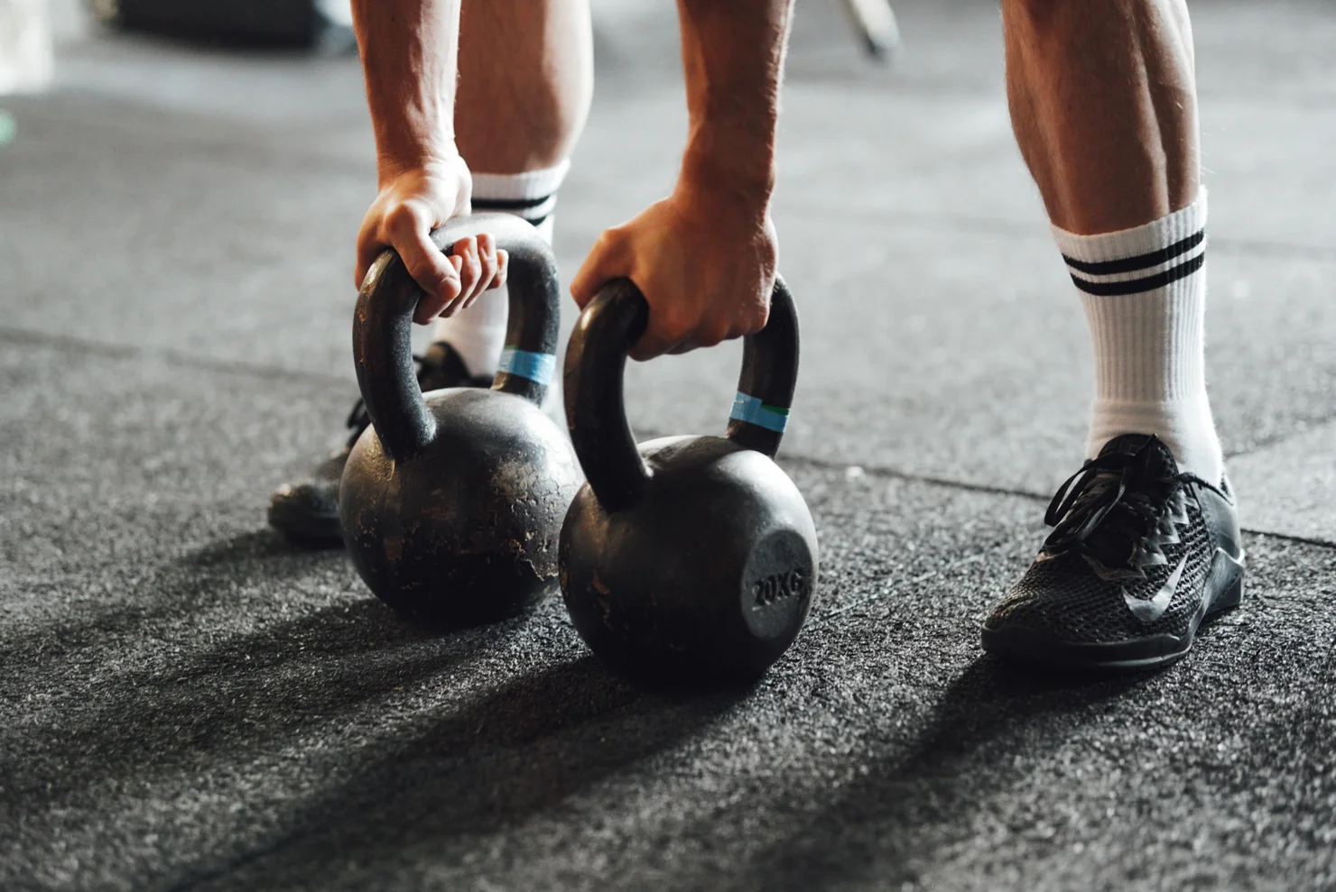 Athlete reaching for two kettlebells on the floor